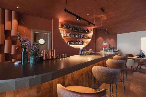 a bar in a restaurant with brown walls and stools at Secrets Baby Beach Aruba Adults Only in Ceru Colorado