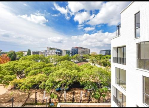 an apartment building with trees and buildings in the background at One Rosebank in Johannesburg