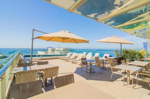 a patio with tables and umbrellas and the ocean at Arena Ipanema Hotel in Rio de Janeiro