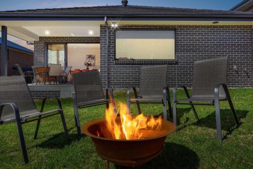 a fire pit in a yard with chairs and a patio at Huntlee Heights in North Rothbury