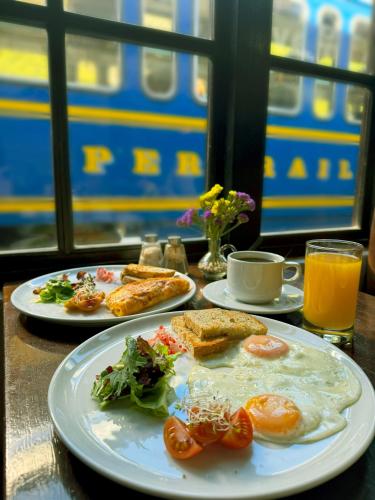 a table with two plates of breakfast food on it at El Albergue Ollantaytambo in Ollantaytambo
