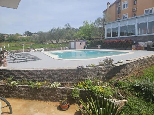 a swimming pool in a yard with a stone wall at Apartments Šeherzada in Pula