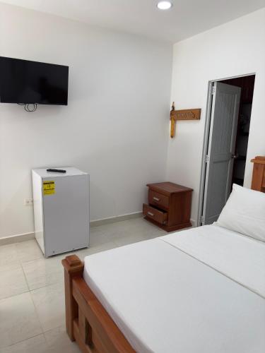 a bedroom with a white bed and a television at Eco hotel el bosque in Doradal