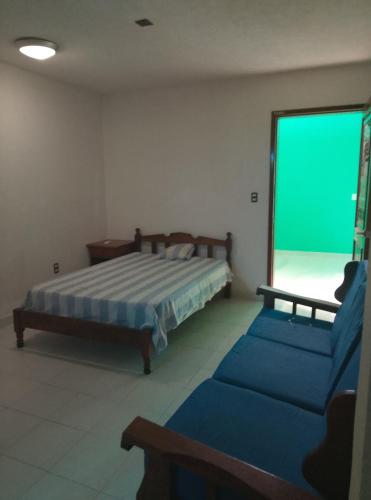 a bedroom with a bed and a couch and a green screen at F H Hostel in Chetumal