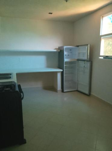 a kitchen with a refrigerator and a table in a room at F H Hostel in Chetumal