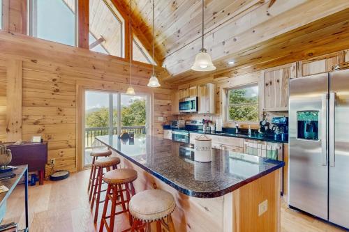 Cabaña de madera con cocina con encimera grande y taburetes en Nanuk, en Needmore