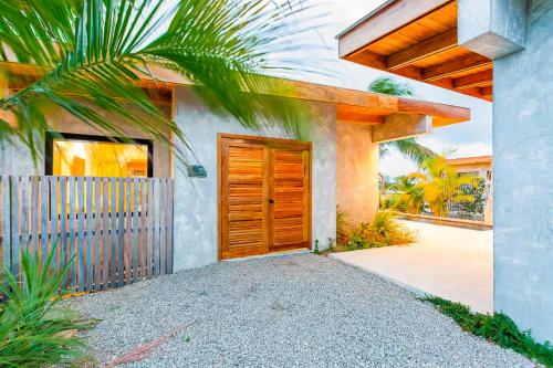 a house with a wooden door and a fence at Seabird - Villa 10 in Placencia Village