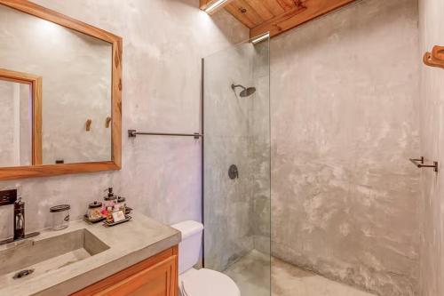 a bathroom with a shower and a toilet and a sink at Seabird - Villa 10 in Placencia Village