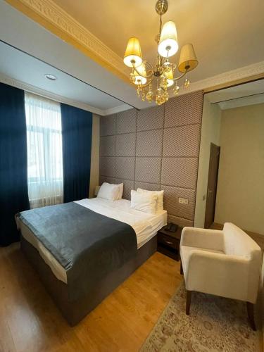 a bedroom with a bed and a chair and a chandelier at TWINS MIRROR group HOTELS in Baku