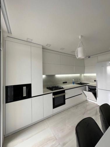 una cucina con mobili bianchi ed elettrodomestici neri di ApartHotel city centrum a Chişinău