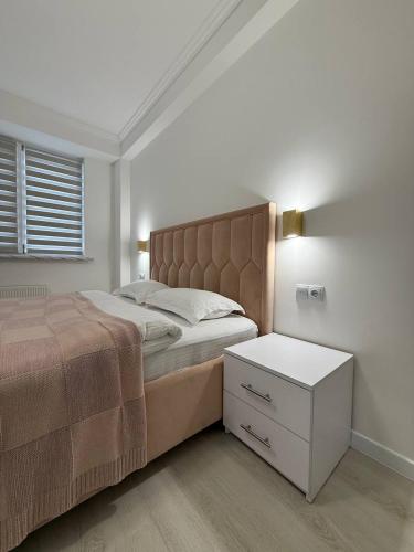 una camera da letto con un letto grande e un comodino bianco di ApartHotel city centrum a Chişinău