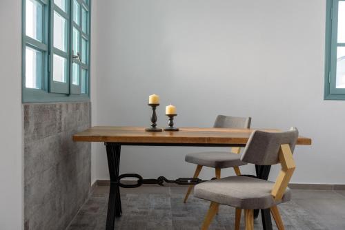 a wooden table with two chairs and two candles on it at Sublime Villa & Caves in Akrotiri