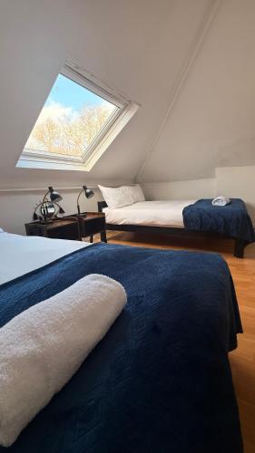 a attic bedroom with two beds and a window at Central located house for big groups in Bristol