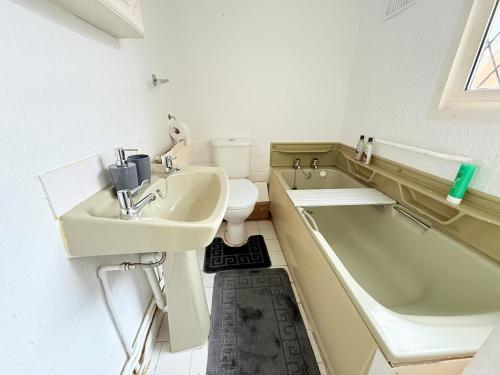 a bathroom with a sink and a tub and a toilet at Homey 4 bedroom house for families or large groups in Canley