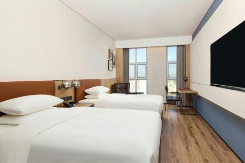 a hotel room with three beds and a flat screen tv at Four Points by Sheraton Yining in Yining
