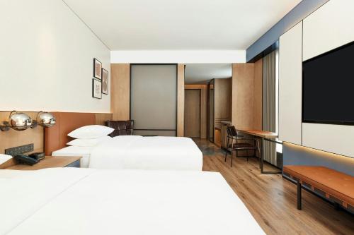 a hotel room with two beds and a flat screen tv at Four Points by Sheraton Yining in Yining
