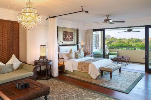 a bedroom with a bed and a couch and a chandelier at The St. Regis Bali Resort in Nusa Dua