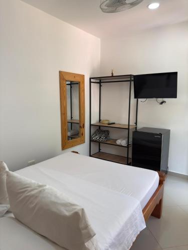 a bedroom with a white bed and a television at Eco hotel el bosque in Doradal