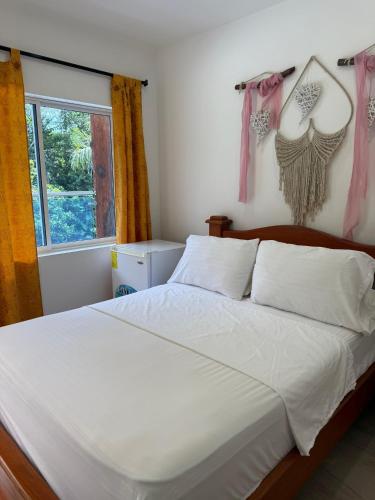 a bedroom with a bed with white sheets and a window at Eco hotel el bosque in Doradal