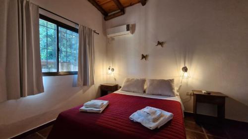 a bedroom with a red bed with towels on it at Altos del Campo in San José