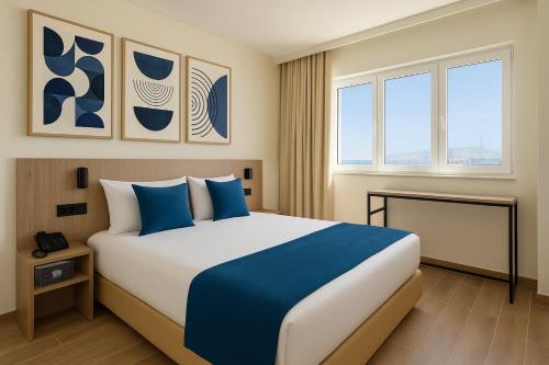 a hotel room with a large bed with blue pillows at Hotel Infante Santo - Lisboa in Lisbon