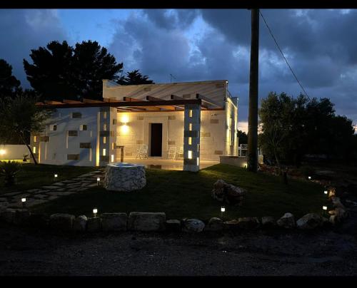 una pequeña casa blanca con luces en el patio en La Casedda, en Carovigno