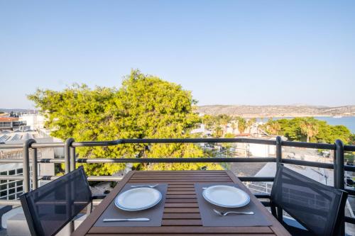 a wooden table on a balcony with a view of the ocean at Azure7 Seaside - Luxury Apartment in Varkiza in Vari