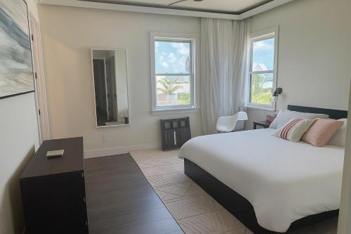 a bedroom with a large bed and two windows at Il Capitano - Little Torch Key in Little Torch Key
