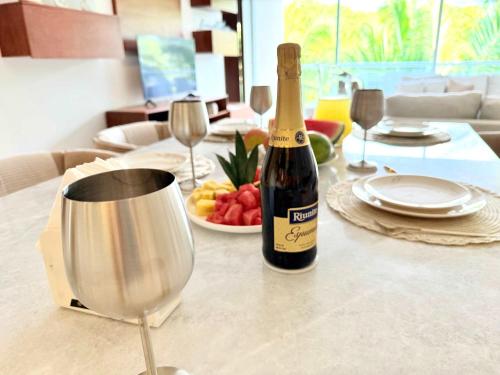 a bottle of wine and a bowl of fruit on a table at Bolongo 2BR your exclusive oceanfront escape in Punta Mita