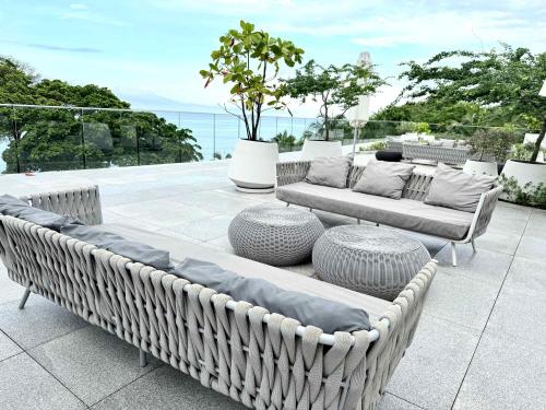 a patio with two wicker couches and two tables at Bolongo 2BR your exclusive oceanfront escape in Punta Mita