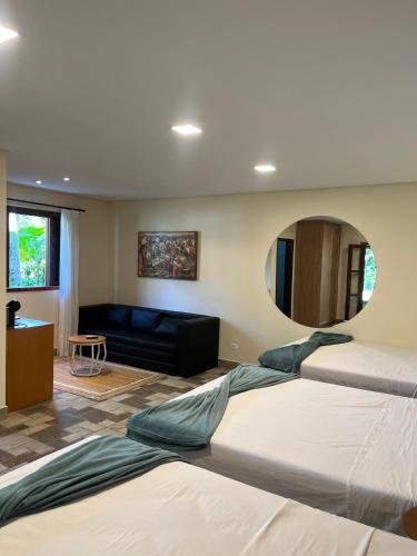 a bedroom with two beds and a couch and a mirror at Pousada Paraíso do Sol in Campo Largo