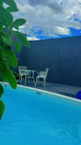 two chairs and a table next to a swimming pool at Casas Paradisiaca Pagamento Automática in Caldas Novas