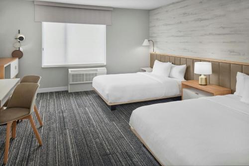 a hotel room with two beds and a table and chairs at TownePlace Suites by Marriott Lansing North in Lansing