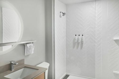 a white bathroom with a shower and a sink at TownePlace Suites by Marriott Lansing North in Lansing