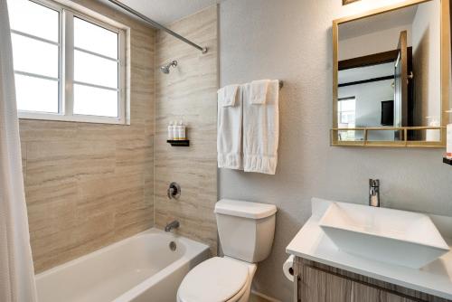 a bathroom with a toilet and a sink and a tub at Tradewinds Apartment Hotel Miami Beach in Miami Beach