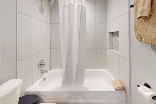 a white bathroom with a tub and a toilet at 103 - La Coquina in St Pete Beach