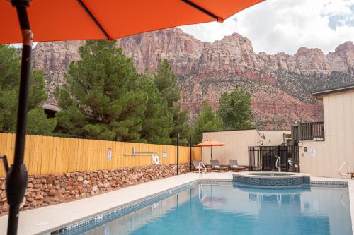 a pool with an umbrella and mountains in the background at Petty Ranch Inn in Springdale