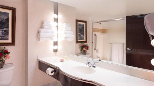 a bathroom with a sink and a toilet and a mirror at Rainbow Hotel Casino by Peppermill Resorts in West Wendover
