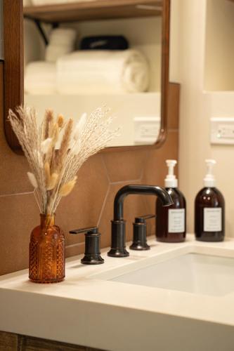 a bathroom sink with a vase of flowers and a mirror at Petty Ranch Inn in Springdale