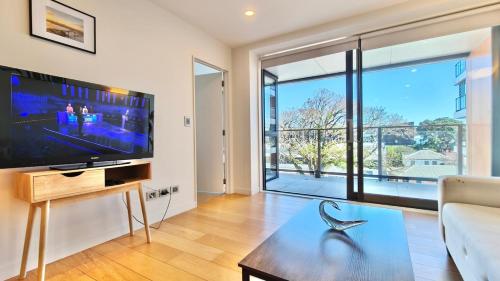 a living room with a large tv and a couch at Spacious 2-Bedroom, 2-Bathroom Apartment in Epsom in Auckland