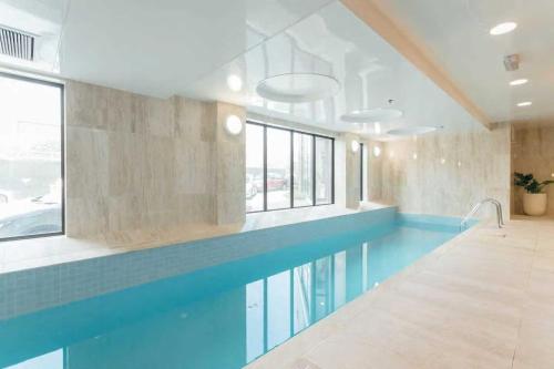 a large swimming pool in a room with a blue swimming pool at Spacious 2-Bedroom, 2-Bathroom Apartment in Epsom in Auckland