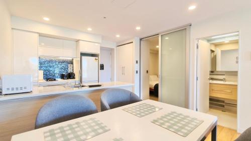 a room with a table and chairs and a kitchen at Spacious 2-Bedroom, 2-Bathroom Apartment in Epsom in Auckland