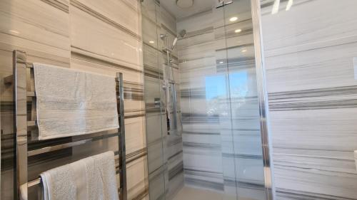 a bathroom with a glass shower with towels at Spacious 2-Bedroom, 2-Bathroom Apartment in Epsom in Auckland