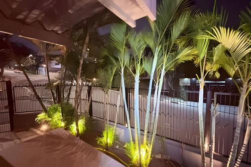 a swimming pool with palm trees and lights at Airport Stay Guarulhos – 600m Bosque Maia, Wi-Fi, Estacionamento, Sala de Espera, piscina, Check-in Facial in Vila Gopoúva