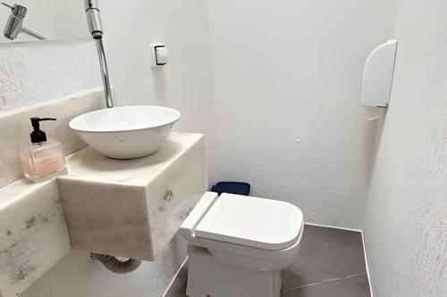 a white bathroom with a sink and a toilet at Airport Stay Guarulhos – 600m Bosque Maia, Wi-Fi, Estacionamento, Sala de Espera, piscina, Check-in Facial in Vila Gopoúva