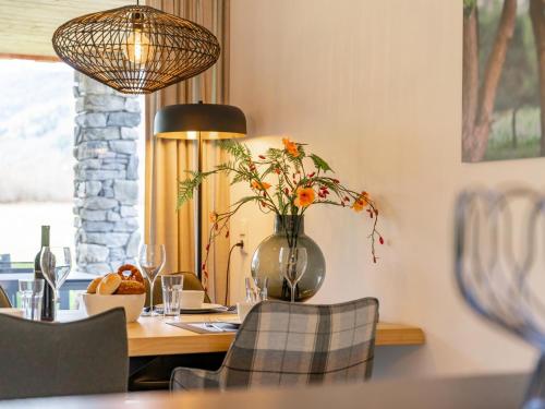 a dining room table with a vase with flowers in it at Mountain Chalet Chapeau in Sankt Lorenzen ob Murau