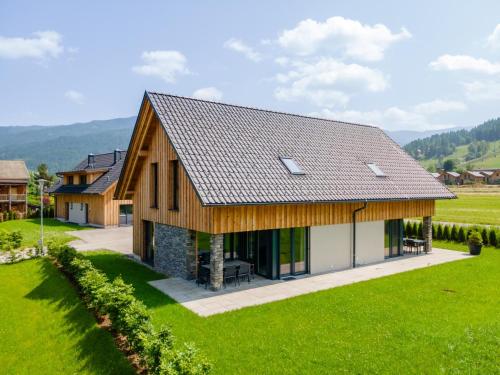 a house with a wooden roof and a green field at Mountain Chalet Chapeau in Sankt Lorenzen ob Murau