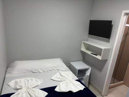 ein kleines Schlafzimmer mit einem Bett und einem Fernseher in der Unterkunft POUSADA e HOSTEL ARAUNA in Cabo Frio