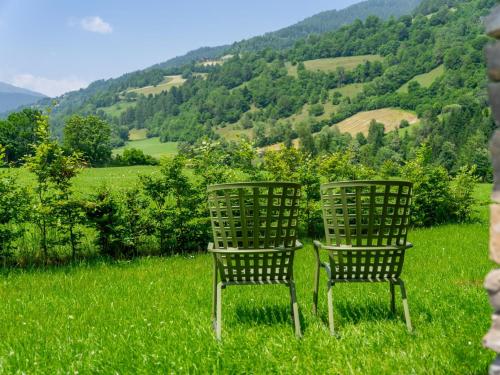two chairs sitting in a field of grass with mountains at Mountain Chalet Krek Wak Wou in Sankt Lorenzen ob Murau