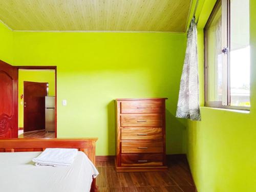 a green room with a bed and a dresser and a window at Cabañas El Manantial in Esquipulas